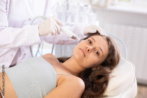 Young girl during beauty procedure of facial skin cleaning with beauty machine attachment