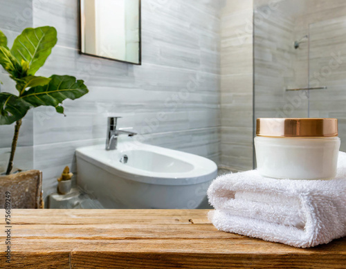 A set of facial cream  towels and a presentation space on a wooden desk in a modern white bathroom.