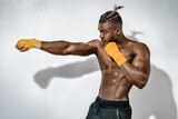 Sporty man during boxing exercise making direct hit. Photo of muscular man with naked torso. Strength and motivation.