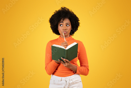 Contemplative young woman with curly hair thoughtfully holding a pencil to her chin