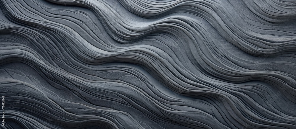 Obraz premium A close up of a swirling grey marble pattern, resembling waves in a dark landscape. The texture is reminiscent of rock or metal, with hints of electric blue and brown tones