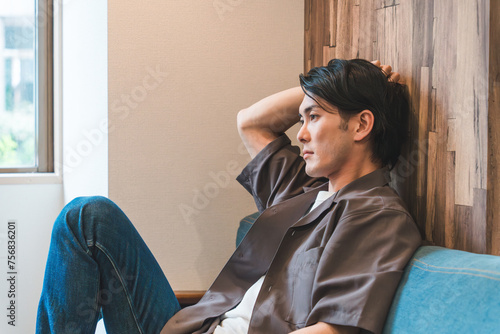 ソファに座って考え事をする男性（悩み・ストレス・うつ病・落ち込む・不安・不満・孤独）
 photo
