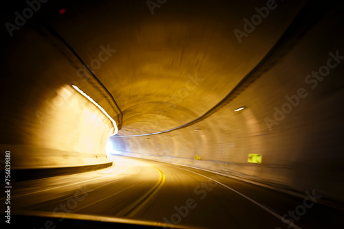 Movimiento rápido. Transitando un túnel curvo en alta velocidad desde un automóvil. Luces ámbar barridas por la rapidez del movimiento. Luz al final del camino. Carretera mexicana. photo