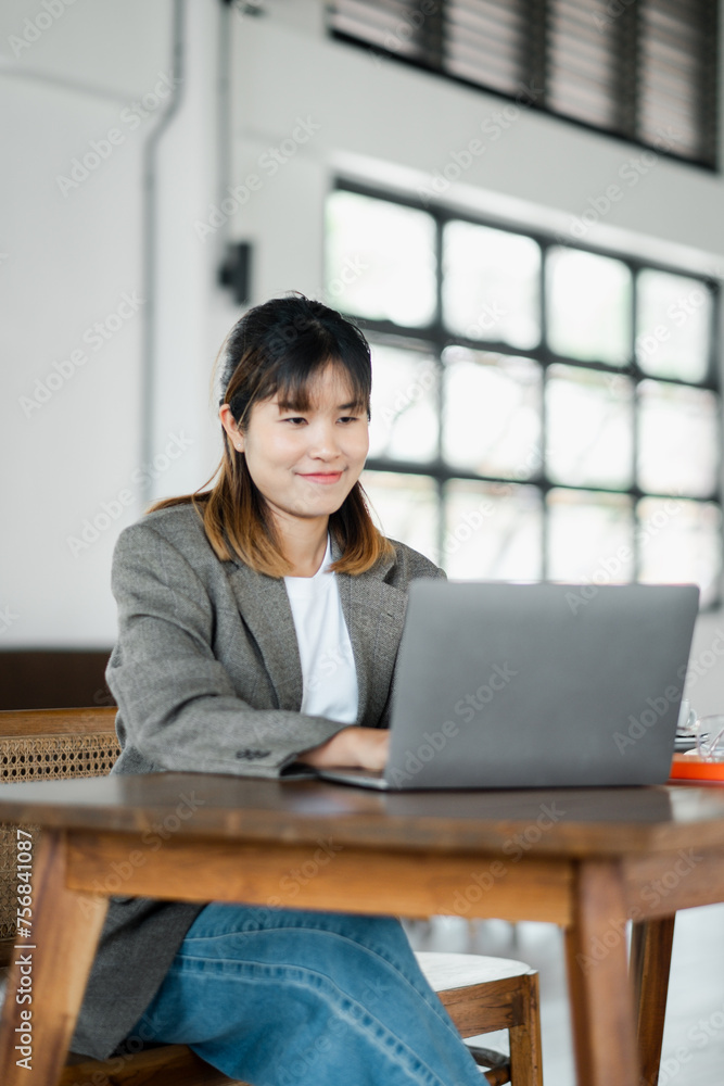 Young businesswoman concentrating on her work on a laptop in a bright office setting with a modern aesthetic. Young businesswoman concentrating on her work on a laptop in a bright office setting with a modern aesthetic.