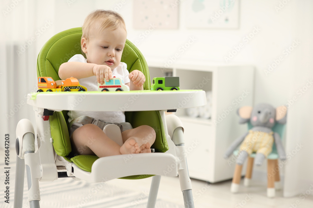 Children toys. Cute little boy playing with toy cars in high chair at home Children toys. Cute little boy playing with toy cars in high chair at home