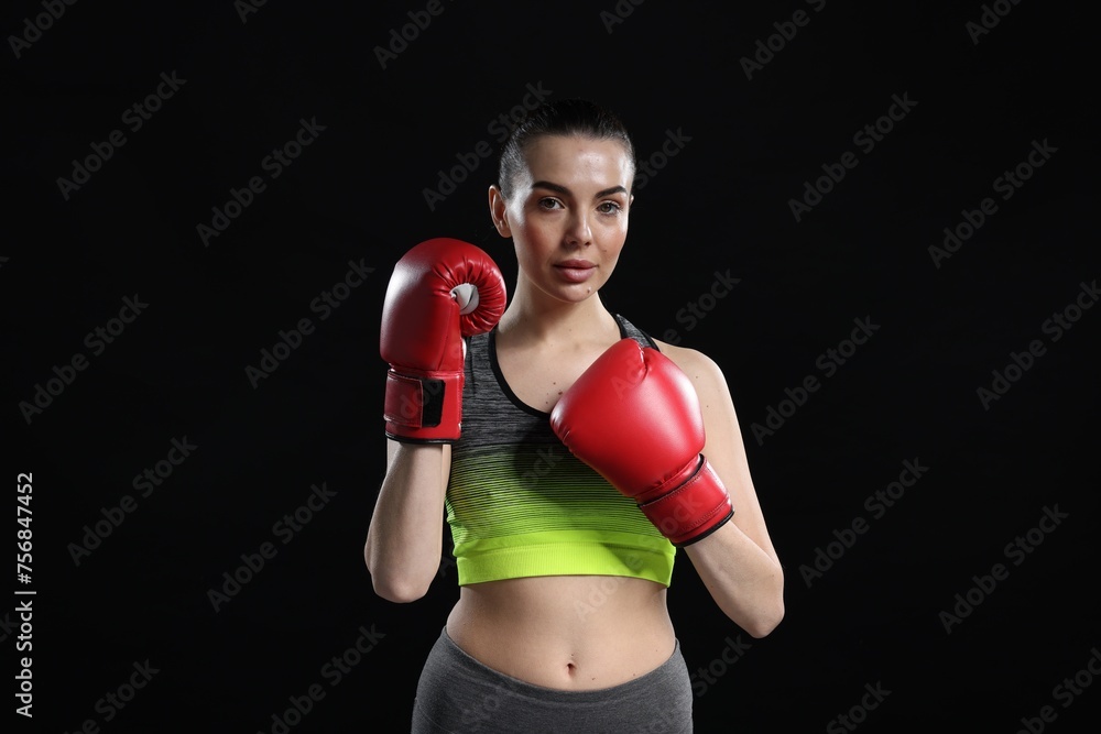 Fototapeta premium Portrait of beautiful woman in boxing gloves on black background