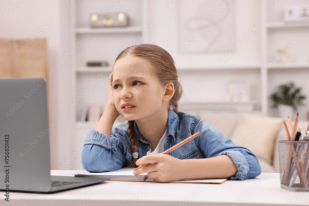 Little girl suffering from headache while doing homework at home Little girl suffering from headache while doing homework at home