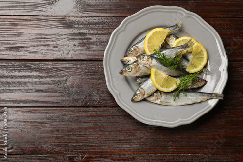 Fresh raw sprats, dill and cut lemon on wooden table, top view. Space for text