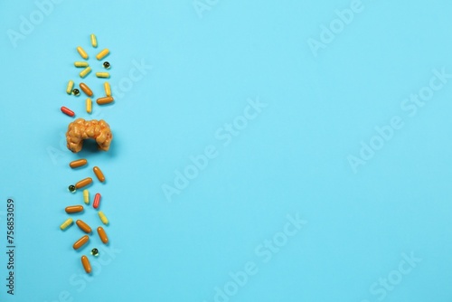 Endocrinology. Capsules and model of thyroid gland on light blue background, top view. Space for text