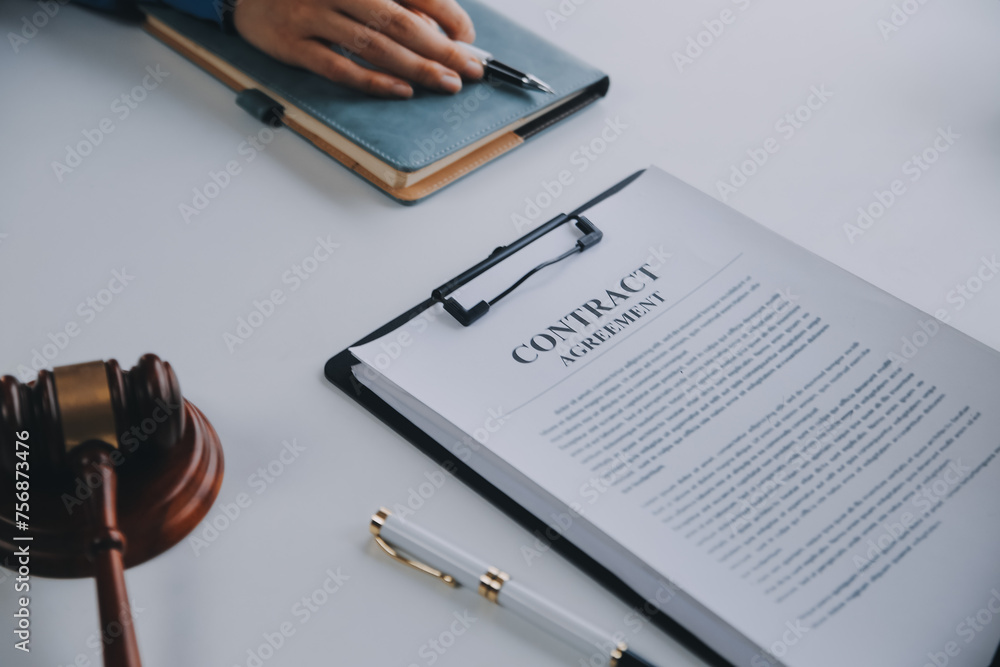 Justice and Law concept. Legal counsel presents to the client a signed contract with gavel and legal law or legal having team meeting at law firm in background