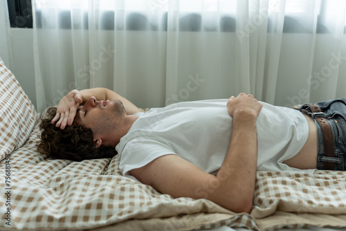 Caucasian handsome man lying down on bed in morning with depression. 