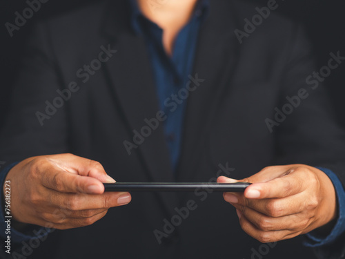 Smartphone in the hands of a businessman against a black background.