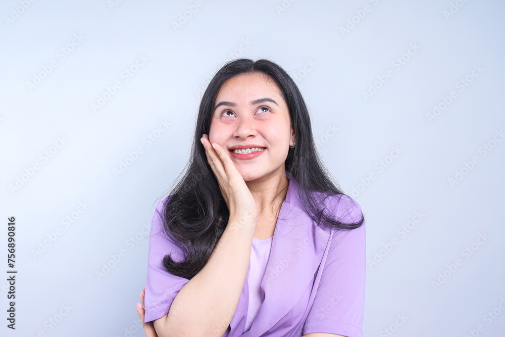 Young Asian woman looking up while smiling isolated on grey background Young Asian woman looking up while smiling isolated on grey background