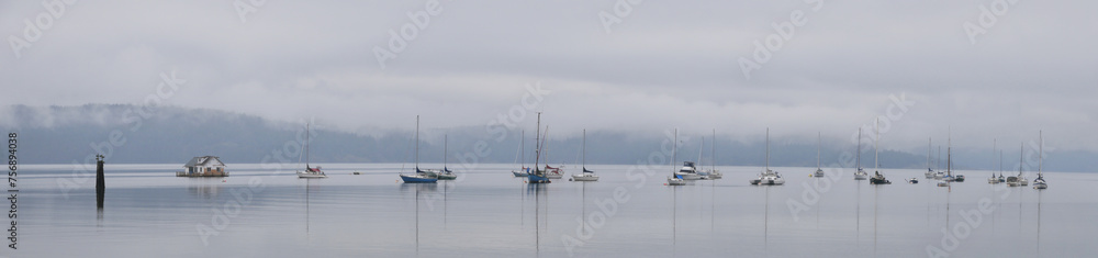 Panorama of boats in front of the shore of Cowichan Bay during a winter season on Vancouver Island in British Columbia, Canada