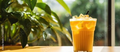 An icecold glass of freshly squeezed orange juice sits on the table, garnished with ice cubes and a straw. The refreshing liquid is the perfect drink for a hot day