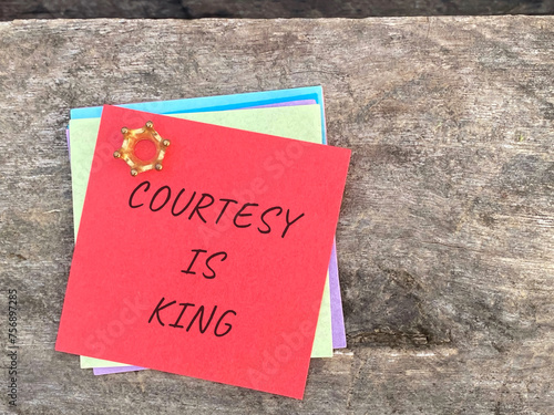Courtesy is king written on red notepaper with retro background. Stock photo.
