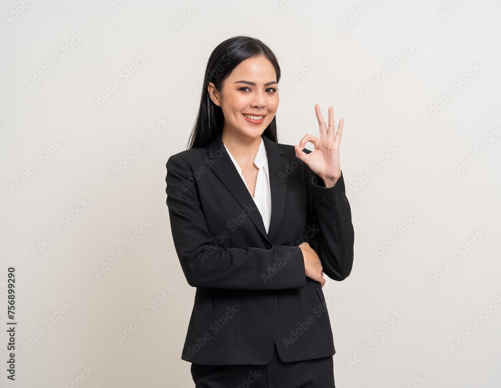 Attractive Young asian business woman showing ok sign looking at camera standing pose on isolated white background. Latin Female around 25 in black suit portrait shot in studio. Attractive Young asian business woman showing ok sign looking at camera standing pose on isolated white background. Latin Female around 25 in black suit portrait shot in studio.