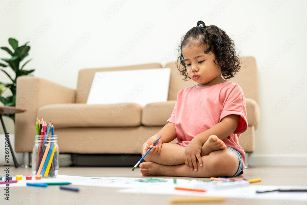 Happy moment little cute girl creating and water color painting activity with paint brushes on frame canvas at living room. Kids activity. Child physical, Emotional, Cognitive development concept. Happy moment little cute girl creating and water color painting activity with paint brushes on frame canvas at living room. Kids activity. Child physical, Emotional, Cognitive development concept.