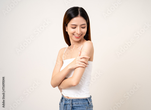 Vaccination. Young beautiful asian woman getting a vaccine protection the coronavirus. Smiling happy female showing arm with bandage after receiving vaccination. On isolated white background. © Chanakon