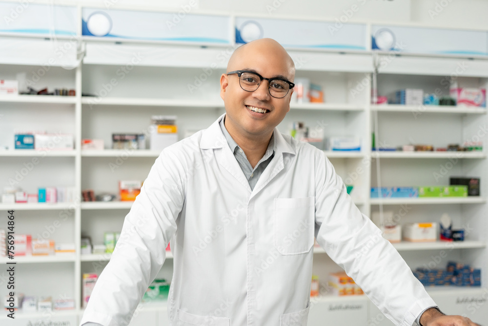 Professional asian man pharmacist checks inventory arrangement of medicine in pharmacy drugstore. Male Pharmacist wearing uniform standing near drugs shelves counter prescription to customers