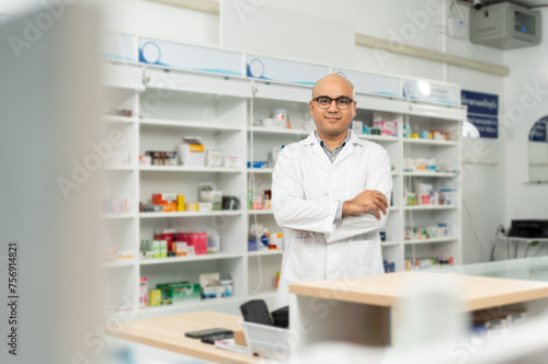 Professional asian man pharmacist checks inventory arrangement of medicine in pharmacy drugstore. Male Pharmacist wearing uniform standing near drugs shelves counter prescription to customers