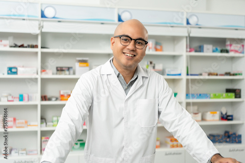 Professional asian man pharmacist checks inventory arrangement of medicine in pharmacy drugstore. Male Pharmacist wearing uniform standing near drugs shelves counter prescription to customers