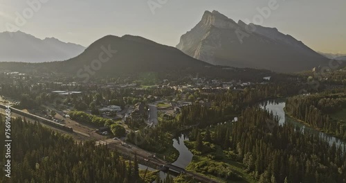 Banff AB Canada Aerial v33 cinematic flyover capturing scenic landscape of train crossing quaint town by the Bow river and Rundle mountain ranges at sunrise - Shot with Mavic 3 Pro Cine - July 2023 photo