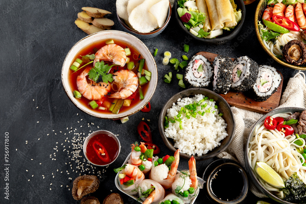 Traditional Asian food table. Spring roll, rice, shrimp, sushi, vegetables, meat on dark background Traditional Asian food table. Spring roll, rice, shrimp, sushi, vegetables, meat on dark background
