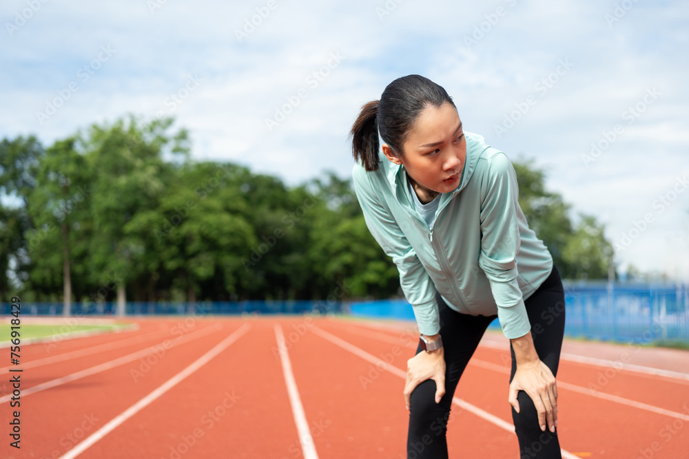 Fototapeta premium Beautiful woman tired during jogging on running track. Young asian female intense training workout challenge breathing exhausted. Exercise in the morning. Healthy and active lifestyle concept.