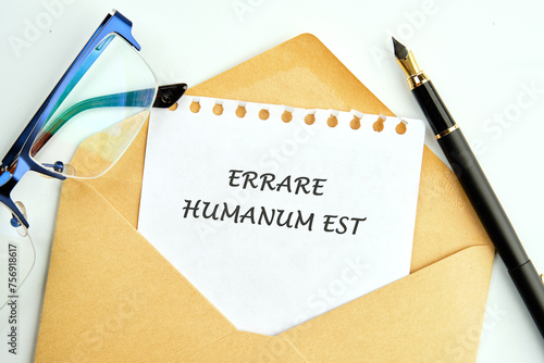 Latin quote Errare humanum est, meaning It is human nature to make mistakes. Mistakes are inherent in human existence. Text written on a sheet in an envelope photo