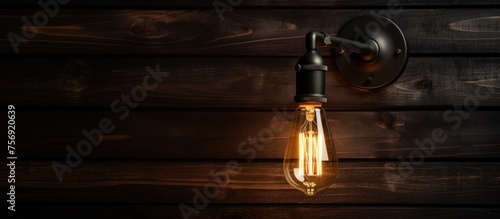 A lamp with automotive lighting is mounted on a hardwood wall, casting tints and shades in the darkness. The wood stain complements the flooring and door handle in the event