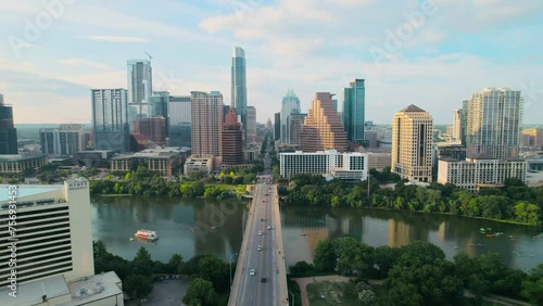 Aerial drone shot of Austin's iconic Congress Avenue bridge and Texas State Capitol overlooking downtown on the Colorado River at sunset, with cars, bikers, and paddleboarders in the river. photo