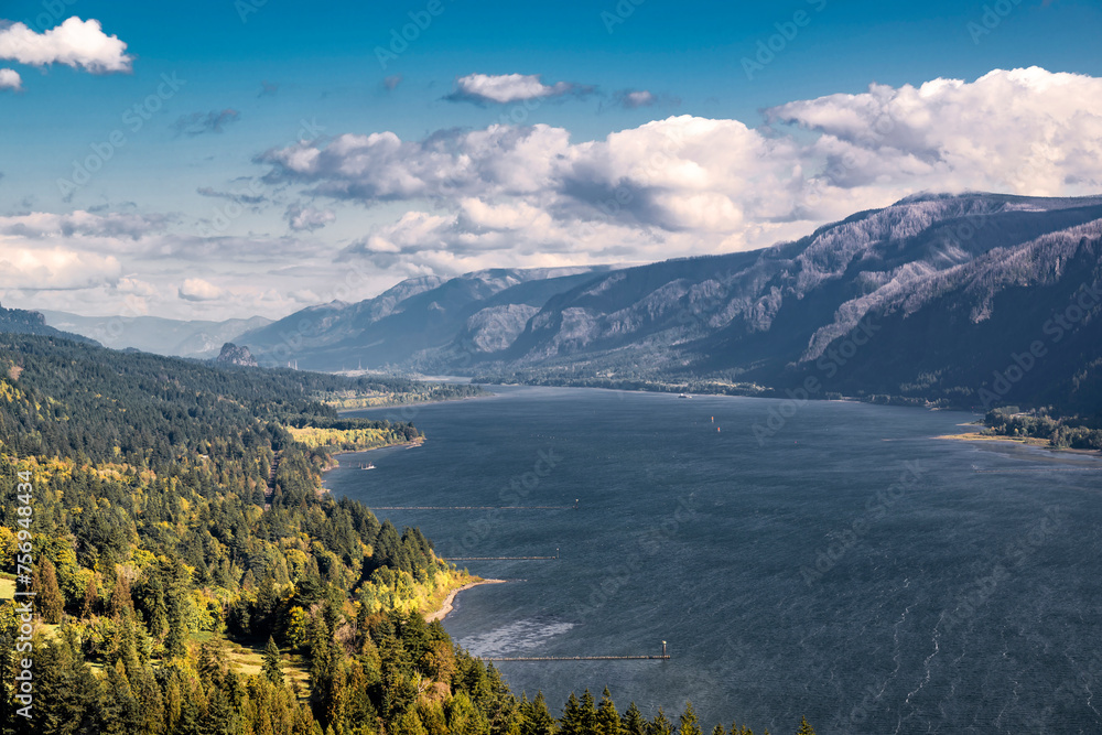 Birds eye view of the Columbia River Gorge showing its winding banks with forested mountain ranges and low cloudy sky