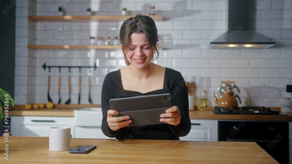 Young woman playing a video game on a tablet computer while sitting in kitchen at home. Excited concentrated woman engrossed in interesting racing game
Young woman playing a video game on a tablet computer while sitting in kitchen at home. Excited concentrated woman engrossed in interesting racing game