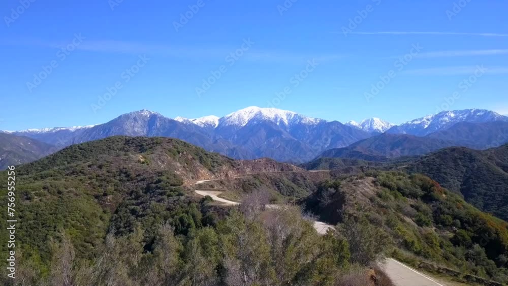 Aerial flyover of a winding mountain road, heading towards snowcapped mountains in the background. Glendora Mountain Road. Aerial flyover of a winding mountain road, heading towards snowcapped mountains in the background. Glendora Mountain Road.