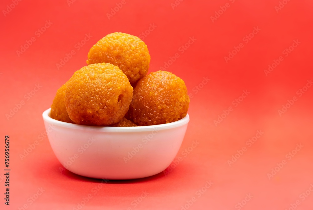 Motichoor Laddu or Motichur Ladoo in a White Bowl Isolated on Red Background with Copy Space Motichoor Laddu or Motichur Ladoo in a White Bowl Isolated on Red Background with Copy Space