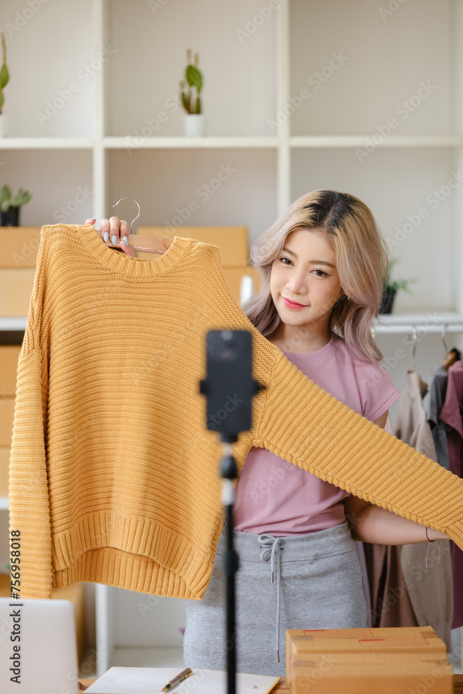 Beautiful Asian woman, blogger, blog, presenting fashion clothes, live video, social media, record her, sell online via digital cameras, sme or small business ecommerce concepts.