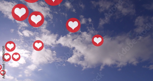 Multiple red heart icons float against a blue sky with clouds