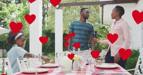 Image of hearts over happy african american family preparing meal in garden