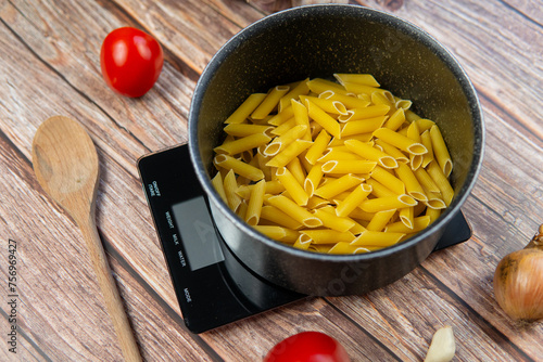 Preparing healthy and nutritious pasta. Weighing pasta on a kitchen scale, counting calories and checking macronutrients. Healthy Mediterranean diet photo