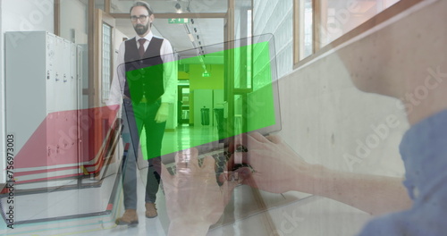Image of businessman using laptop with green screen over businessman walking in office corridor