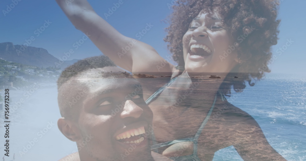 Fototapeta premium Image of happy african american couple having fun at beach over sea