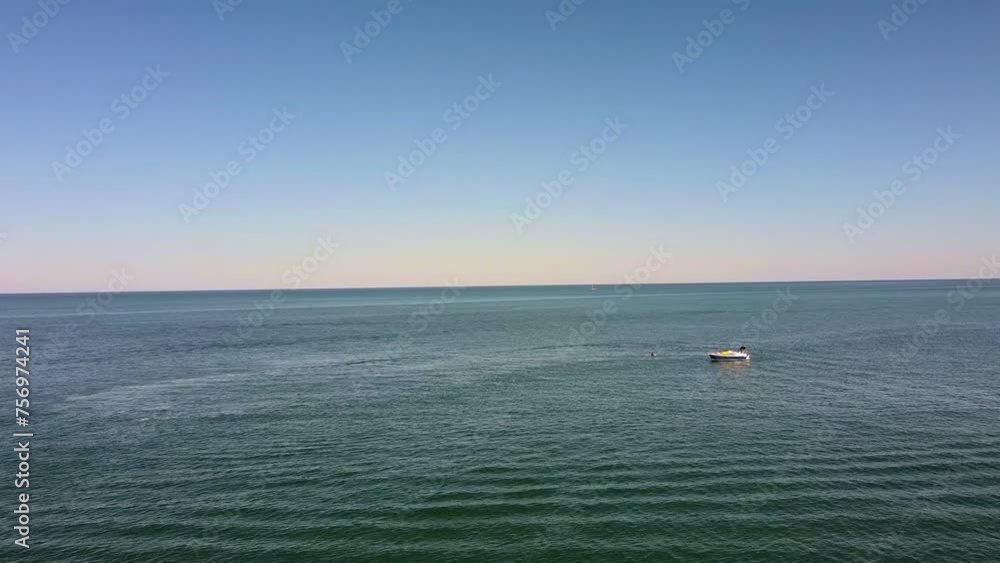 Aerial flyover calm ocean with small boat enjoying watersports Aerial flyover calm ocean with small boat enjoying watersports