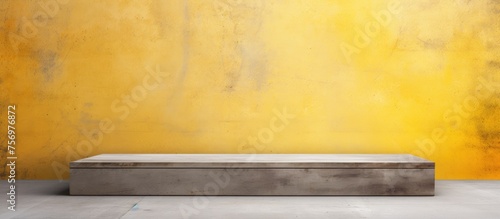 A rectangular wooden podium stands on the hardwood floor in front of a vibrant yellow wall, creating a striking contrast of tints and shades. A horizon painting hangs above the art display photo