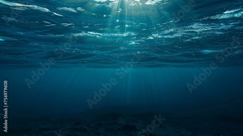 Underwater view with sunbeams shining through the ocean's surface, creating a serene and ethereal blue world.