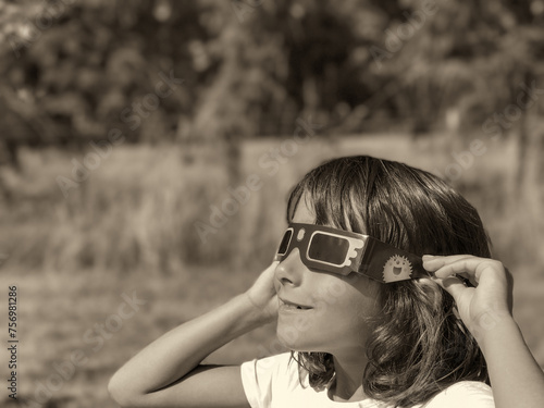 A young girl looking at the sun during a solar eclipse on a country park, family outdoor activity
