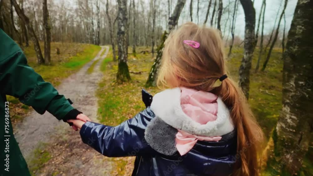 Daughter walks, holding her mother hand, through a nature reserve, filmed from behind Daughter walks, holding her mother hand, through a nature reserve, filmed from behind