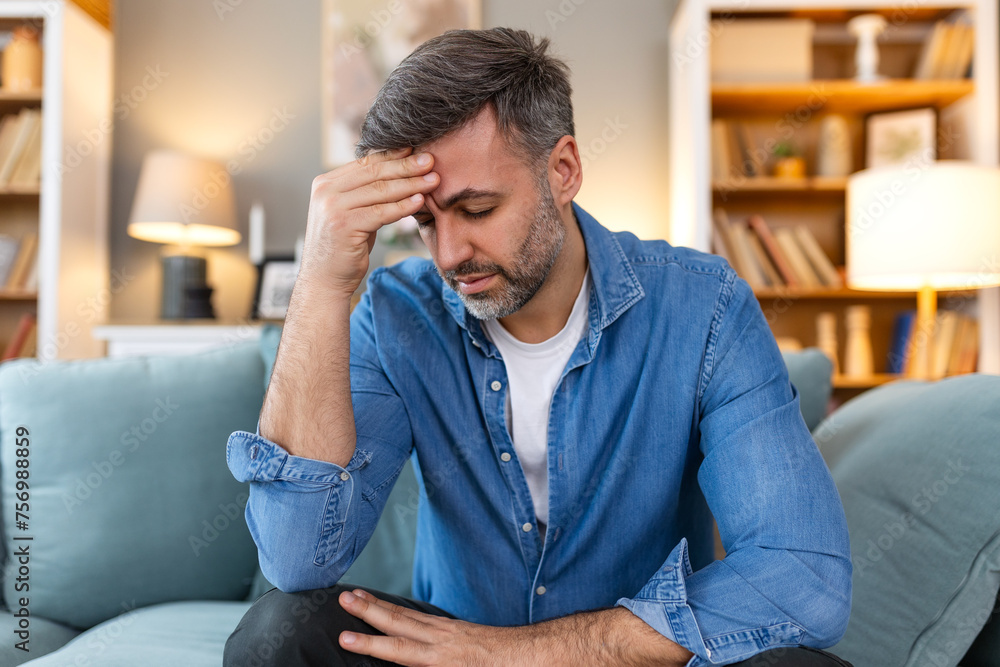 Closeup of man suffering from headache at home, touching his temples, copy space, blurred background. Migraine, headache, stress, tension problem, hangover concept Closeup of man suffering from headache at home, touching his temples, copy space, blurred background. Migraine, headache, stress, tension problem, hangover concept