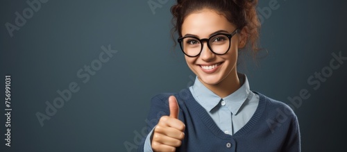 A woman with glasses is smiling, giving a thumbs up gesture with her hand, showcasing her vision care and stylish eyewear while highlighting her jawline
