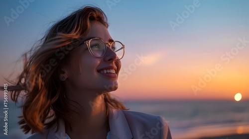 Cheerful Professional Woman with Glasses Overlooking a Tranquil Coastline at Twilight photo